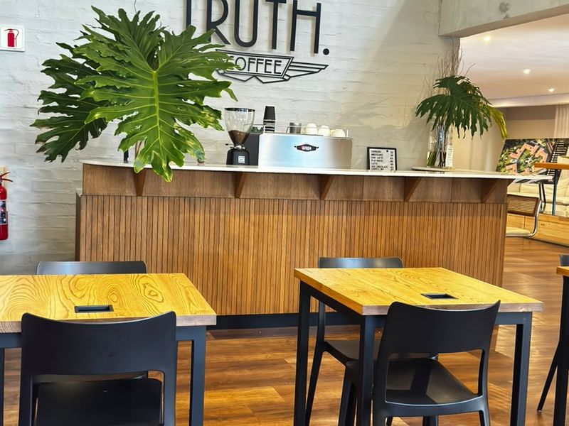 A modern coffee bar area featuring a built-in timber-look counter, exposed brick wall, and durable laminate flooring in a well-maintained commercial or communal space.