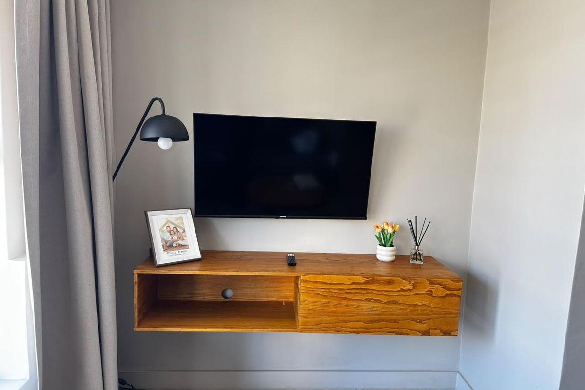 A living room area featuring a wall-mounted timber media console and neutral wall finishes.