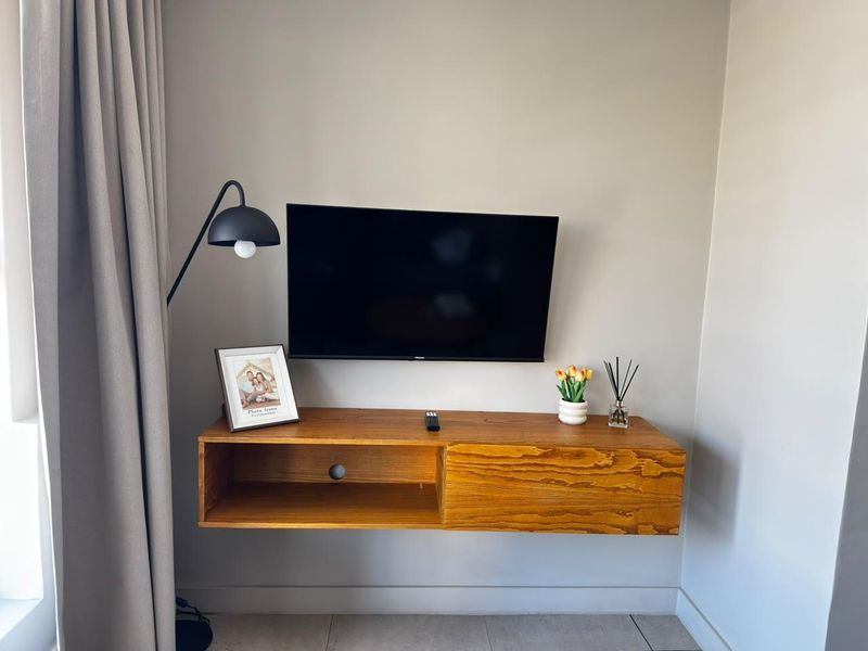 A living room area featuring a wall-mounted timber media console and neutral wall finishes.