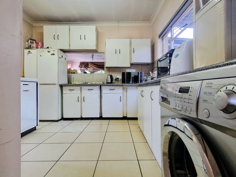 A functional kitchen featuring tiled flooring, built-in cabinetry, and laminate countertops, offering a practical layout with potential for modern updates.