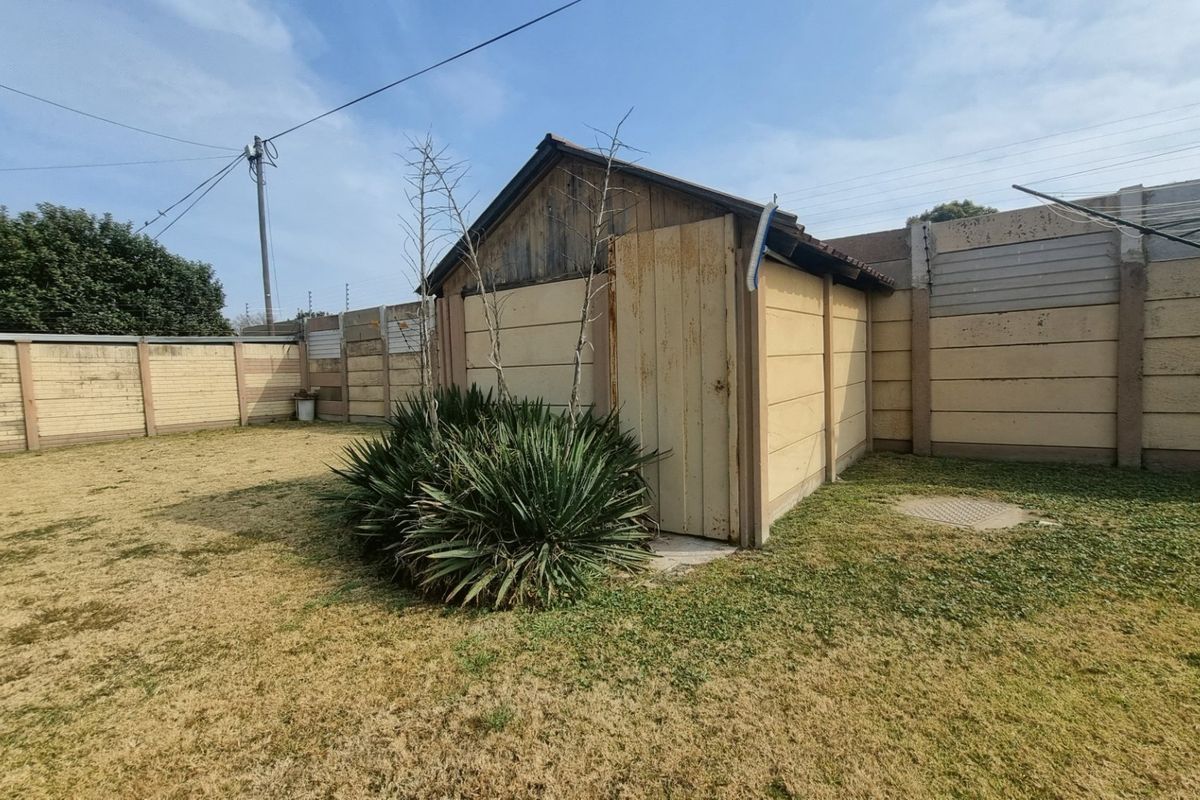 Rear garden area featuring a small outbuilding, precast concrete boundary walls with electric fencing, and a rotary clothesline.
