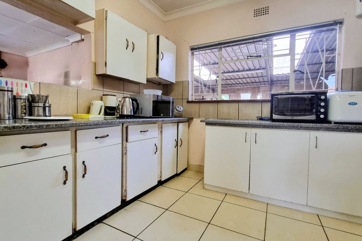 A functional kitchen featuring tiled flooring, laminate countertops, and original built-in cabinetry, offering potential for a modern renovation.
