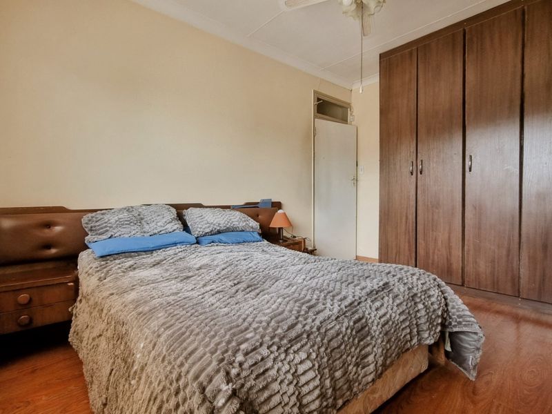 A bedroom featuring laminate flooring, a ceiling fan, and ample built-in cupboard storage space.