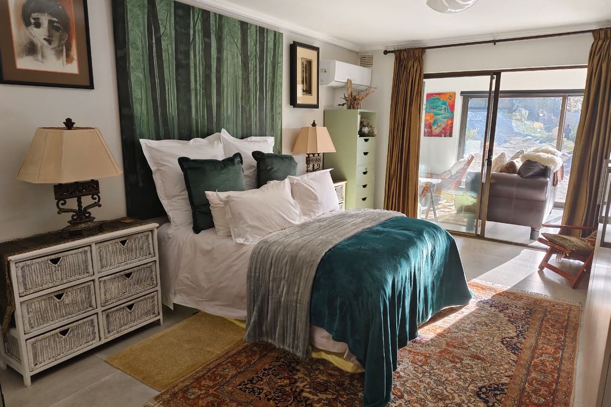 A well-lit bedroom featuring tiled flooring, a split-system air conditioner, and large sliding glass doors providing access to an outdoor patio area.