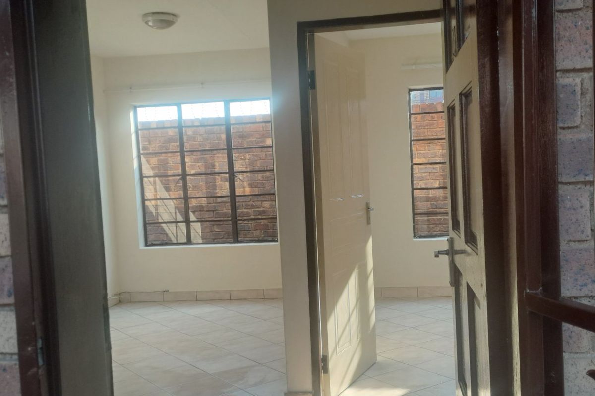 An empty bedroom featuring tiled flooring, neutral walls, and steel-framed windows, offering a clean and functional space ready for personalization.