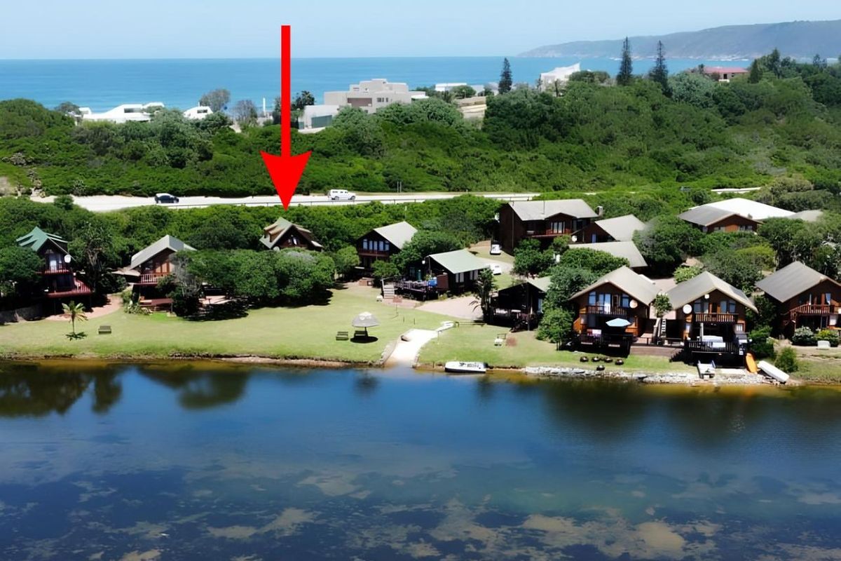 Aerial view of a waterfront residential estate featuring multiple timber-framed houses set within a landscaped coastal environment.