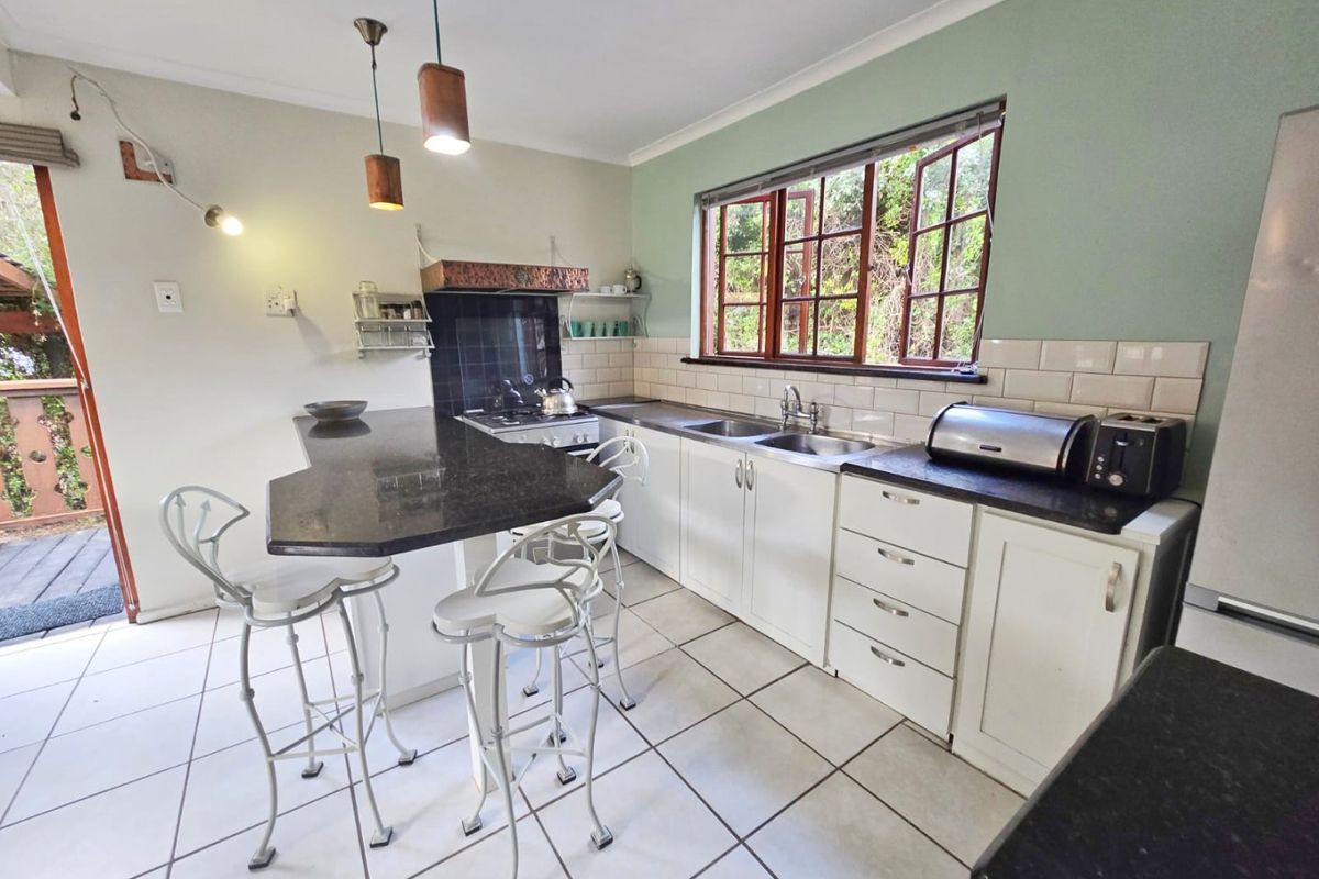 A functional kitchen featuring granite countertops, a double basin sink, subway tile backsplash, and a gas stove with direct access to an outdoor deck.