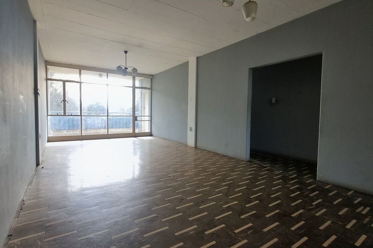 A spacious, empty living area featuring large glass sliding doors that provide natural light and access to an outdoor space.