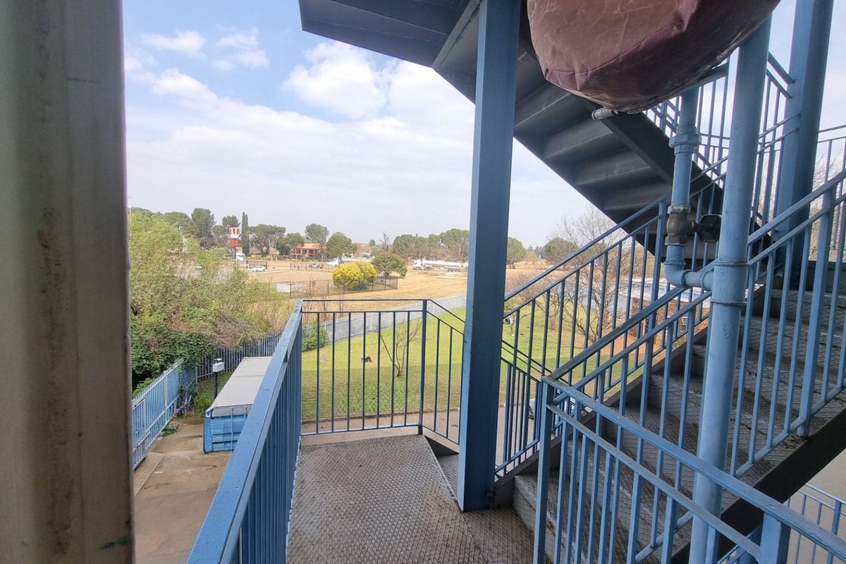 Exterior metal staircase and landing providing access to the apartment, showing signs of weathering and paint deterioration.