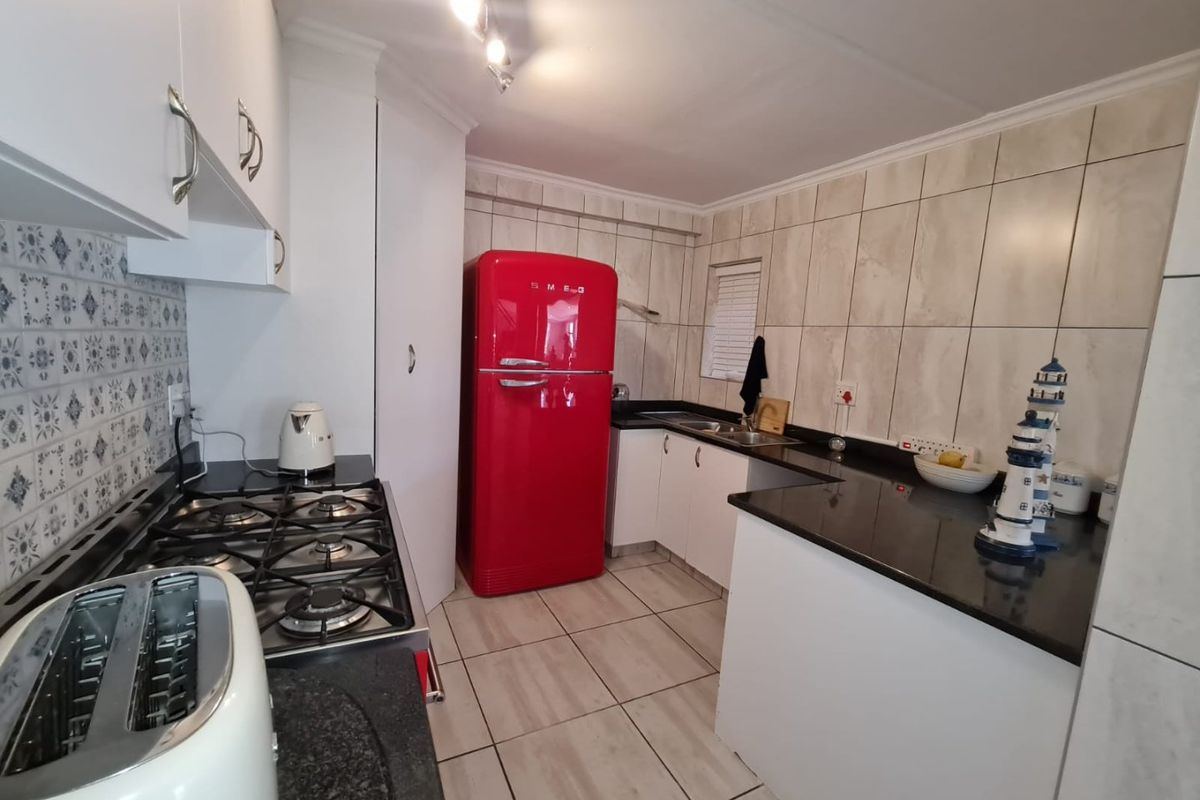 A functional kitchen featuring granite countertops, a gas hob, tiled backsplash, and ample built-in cabinetry with a clean, modern layout.