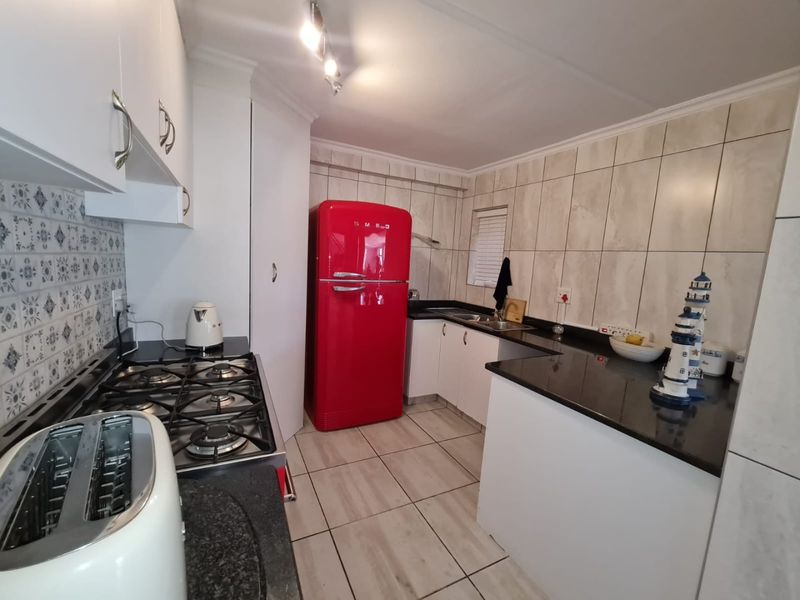 A functional kitchen featuring granite countertops, a gas hob, tiled backsplash, and ample built-in cabinetry with a clean, modern layout.
