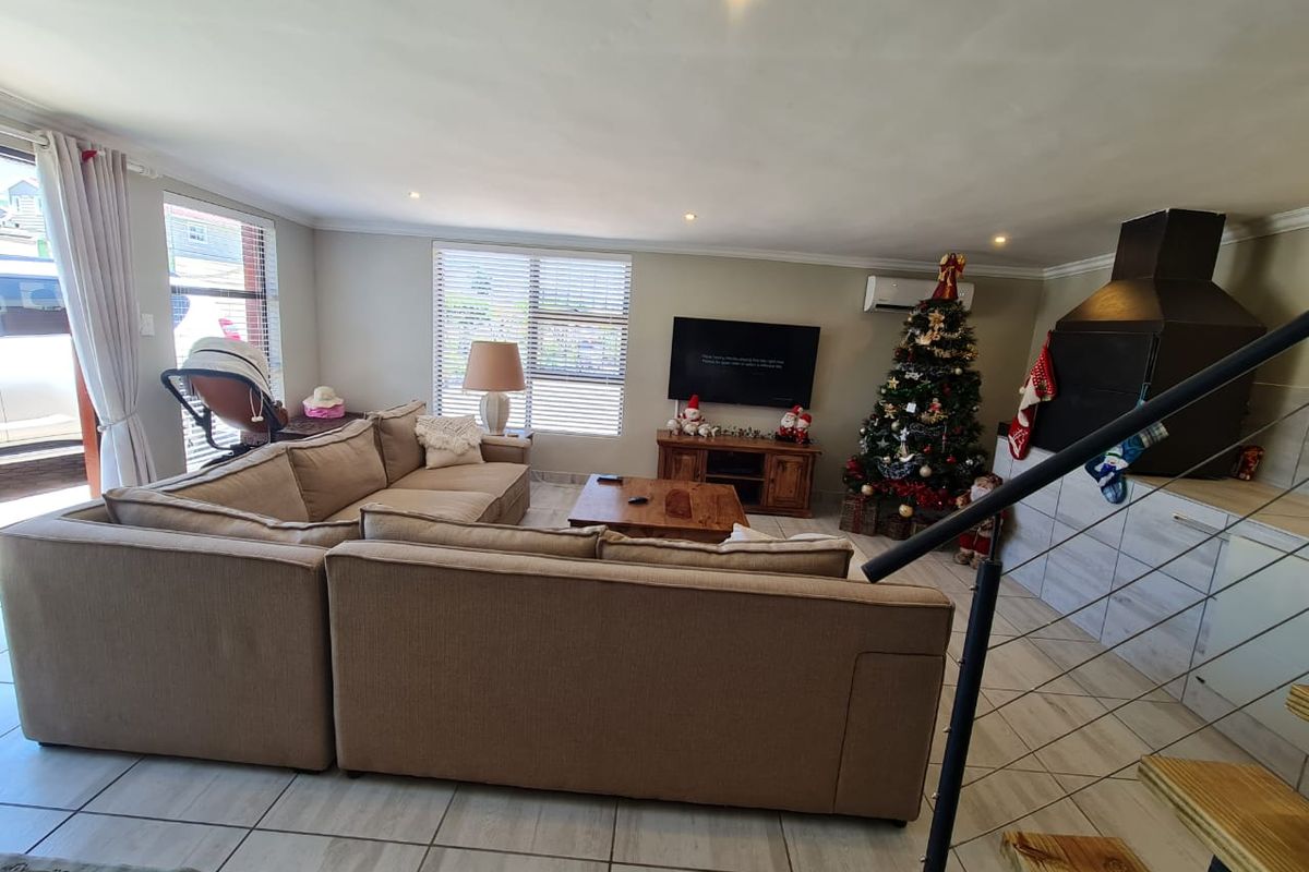 Spacious living room featuring tiled flooring, recessed lighting, a built-in indoor braai, and an integrated air conditioning unit.