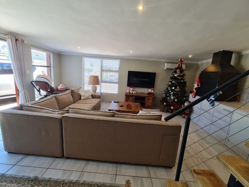 Spacious living room featuring tiled flooring, recessed lighting, a built-in indoor braai, and an integrated air conditioning unit.
