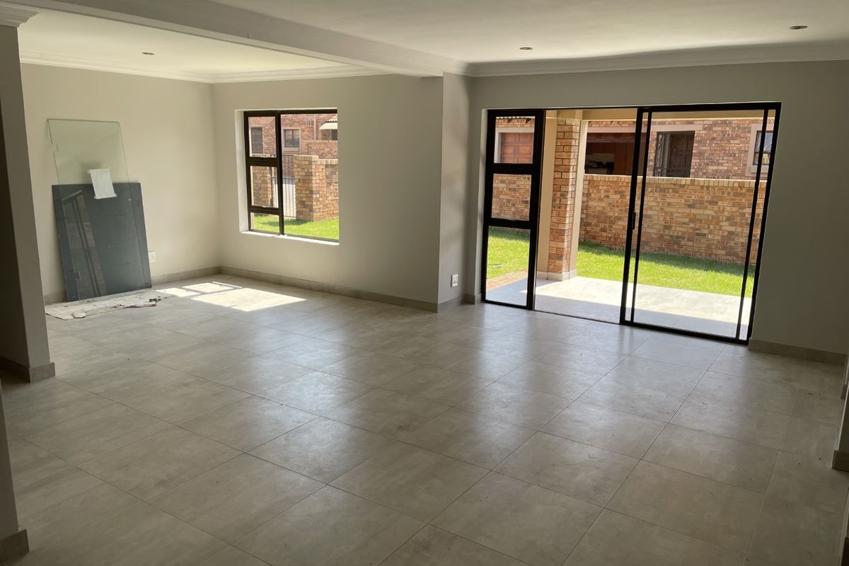 Spacious, light-filled living area featuring neutral tiled flooring, recessed lighting, and large sliding glass doors providing direct access to the rear patio and garden.