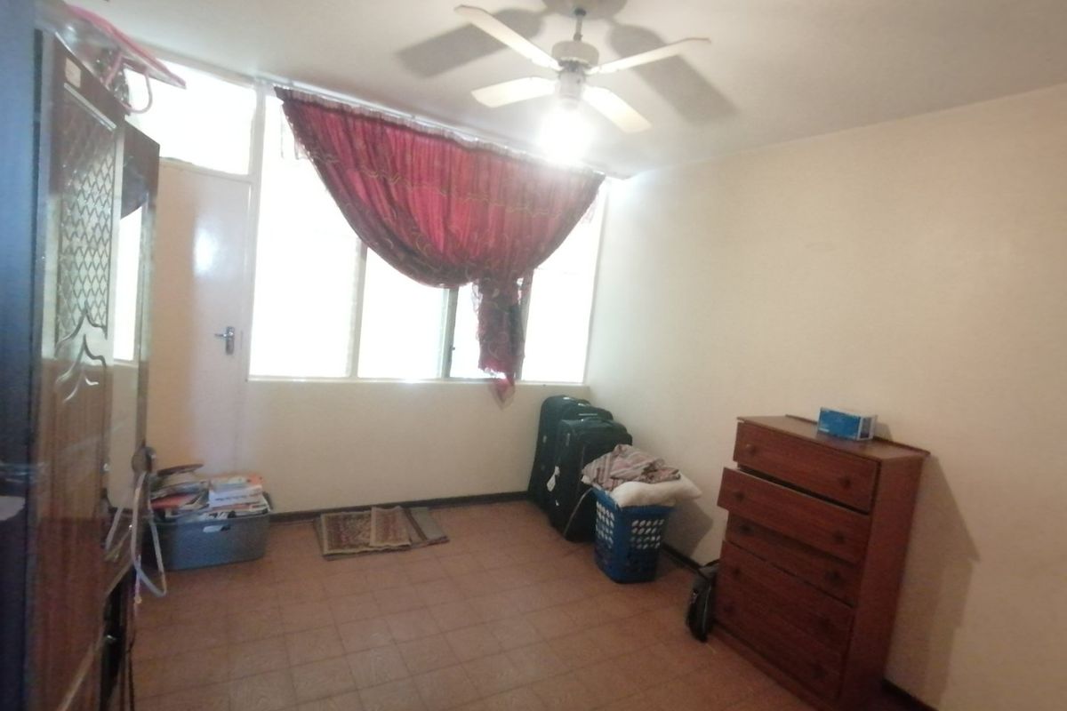 A bedroom featuring tiled flooring and a ceiling fan, offering a functional space with natural light from the window.