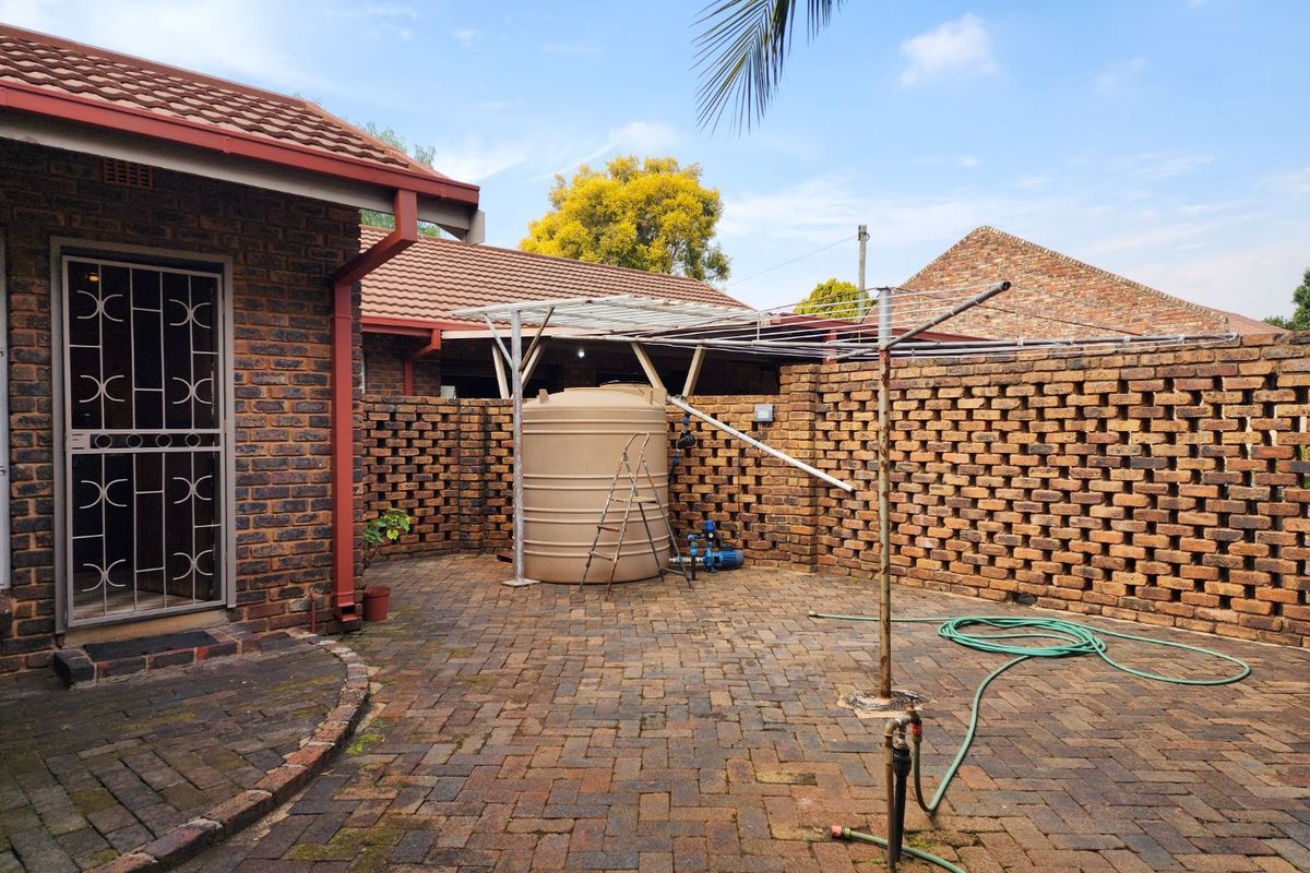 Rear courtyard area featuring brick paving, a water storage tank, and a rotary clothesline, enclosed by a face brick boundary wall.