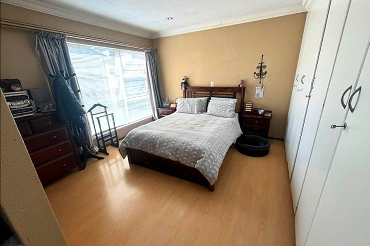 A functional bedroom featuring light laminate flooring, built-in cupboards, and recessed downlighting, offering a neutral space ready for personalization.
