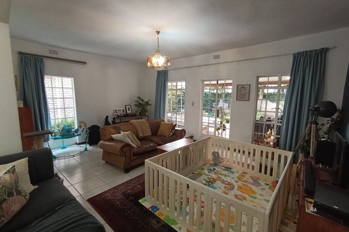 Spacious living room featuring tiled flooring, multiple windows, and french doors providing natural light and access to the outdoor area.