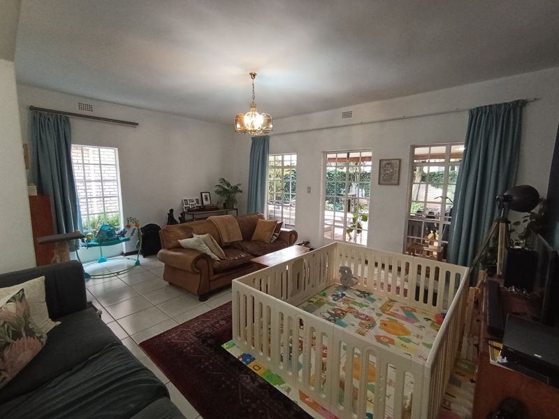 Spacious living room featuring tiled flooring, multiple windows, and french doors providing natural light and access to the outdoor area.