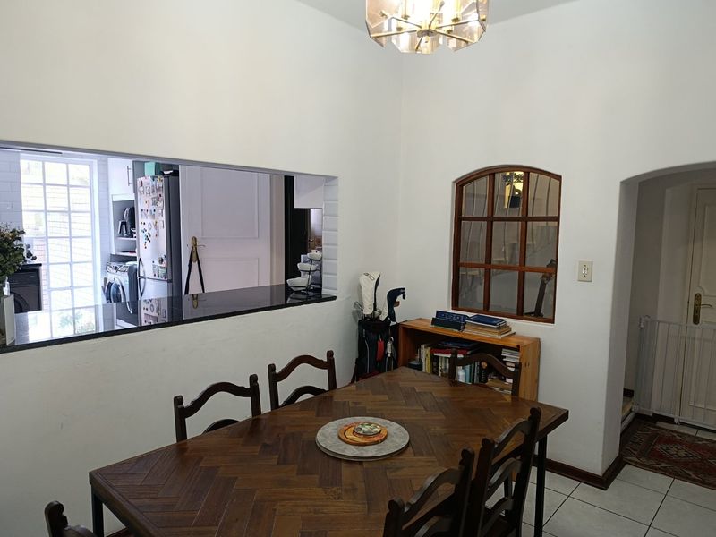 Dining area featuring a granite breakfast bar pass-through to the kitchen, an arched interior window, and tiled flooring.