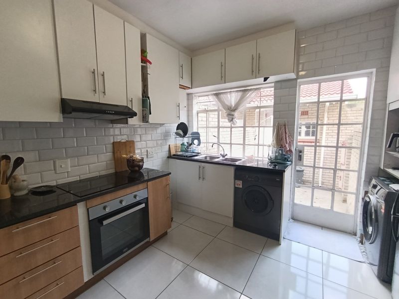 A functional kitchen featuring white and wood-tone cabinetry, granite countertops, subway tile backsplash, and direct access to the exterior through a glass panel door.