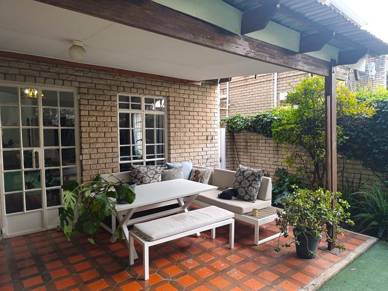 Covered outdoor patio featuring terracotta tiling, facebrick walls, and a timber pergola structure, providing a functional space for outdoor relaxation.