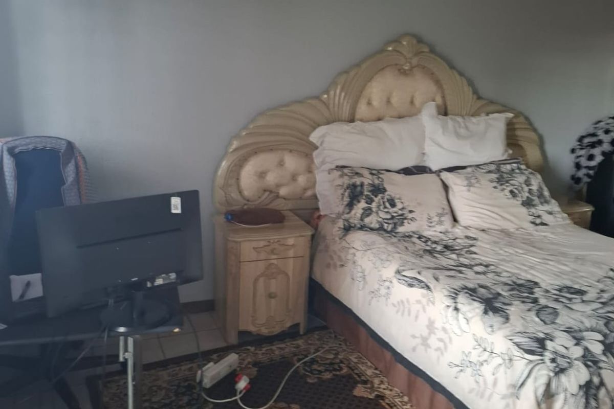 A bedroom featuring tiled flooring and a wall-mounted light fixture, offering a functional space ready for personalization.