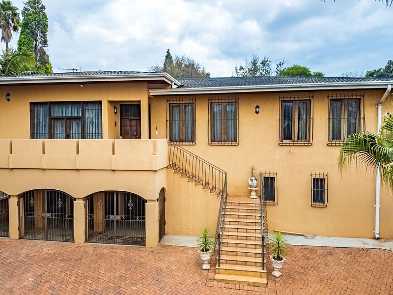 Front elevation of a multi-level house featuring a brick paved driveway, arched garage bays, and an external staircase leading to the main entrance.