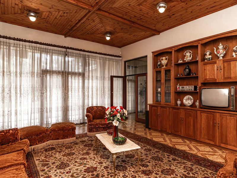 Spacious living room featuring a distinctive timber coffered ceiling, extensive built-in wooden cabinetry, and large glass doors providing ample natural light.
