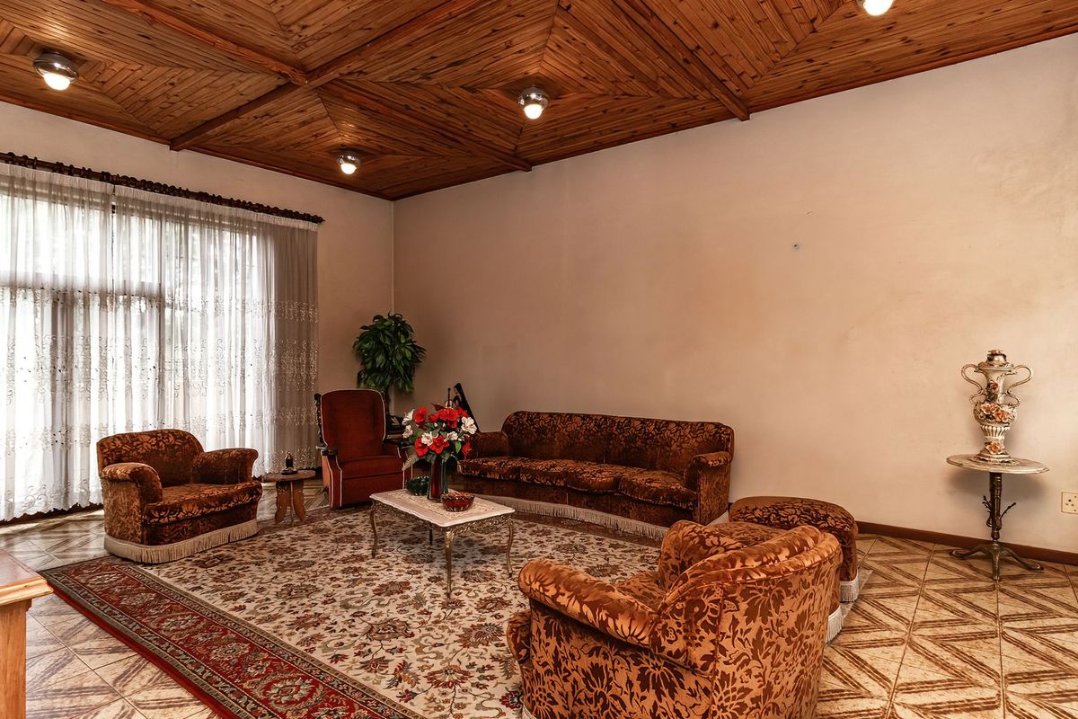 Spacious living room featuring a distinctive timber-clad ceiling, ceramic tiled flooring, and large windows allowing for ample natural light.