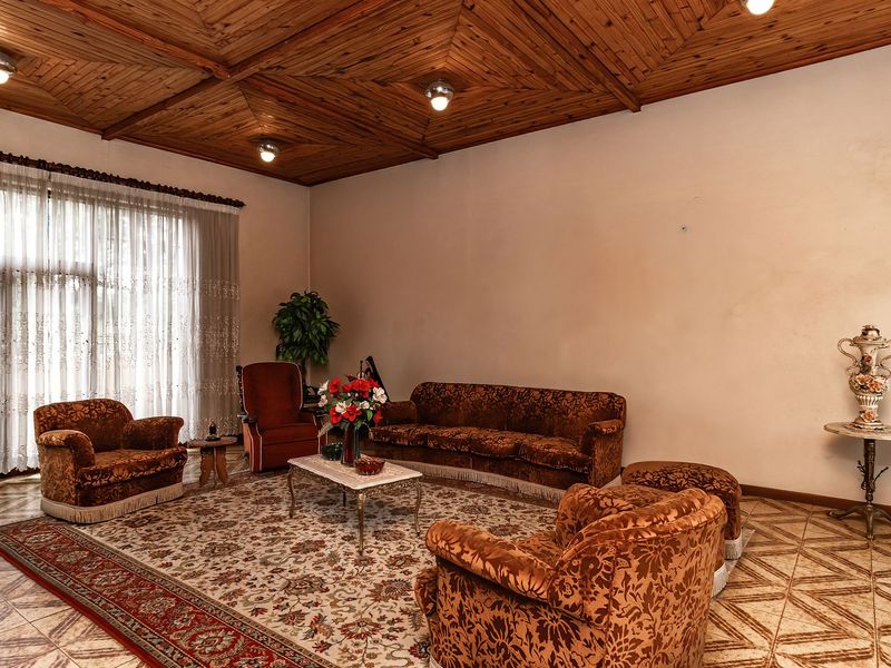 Spacious living room featuring a distinctive timber-clad ceiling, ceramic tiled flooring, and large windows allowing for ample natural light.