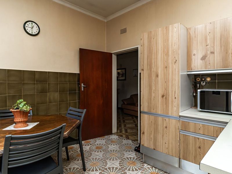 A functional kitchen featuring wood-look cabinetry, tiled splashbacks, and patterned floor tiles, providing a practical space for meal preparation and dining.