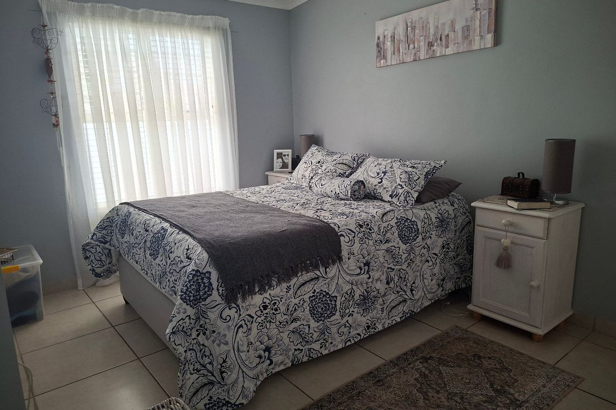 A well-lit bedroom featuring neutral wall tones and tiled flooring, providing a comfortable and functional sleeping space.
