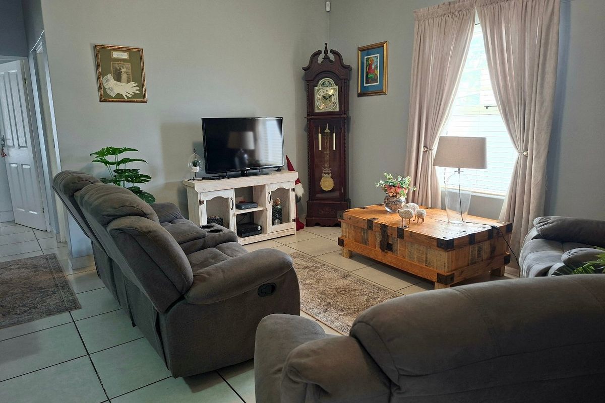 A comfortable living room featuring tiled flooring and natural light through window curtains, providing a functional and inviting space.