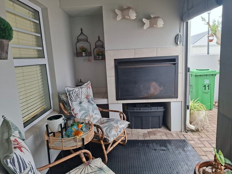 Covered patio area featuring a built-in braai with tiled surround and paved flooring, providing a functional outdoor entertainment space.