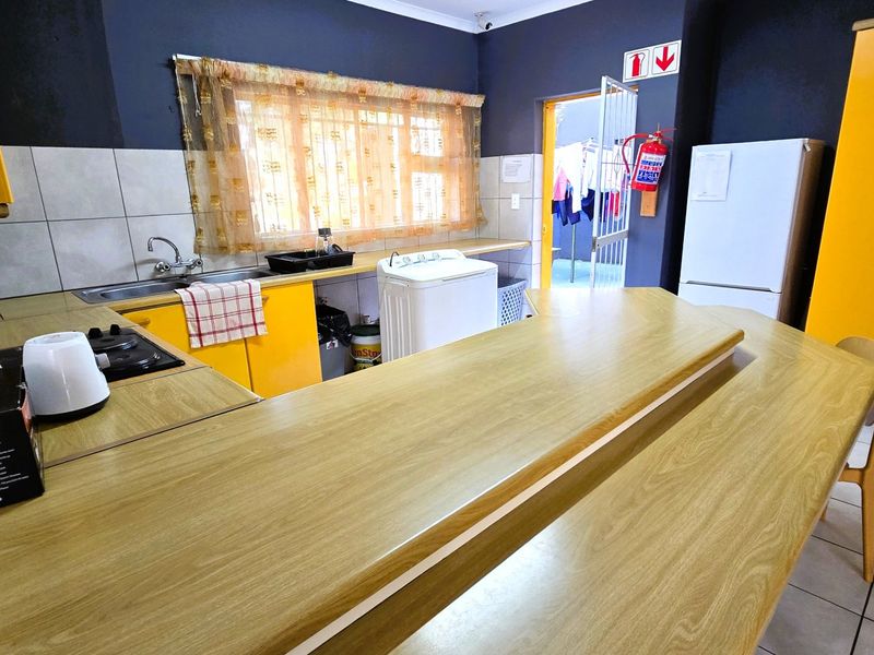 Functional kitchen featuring yellow built-in cabinetry, laminate countertops, a stainless steel sink, and tiled flooring with direct access to an outdoor area.