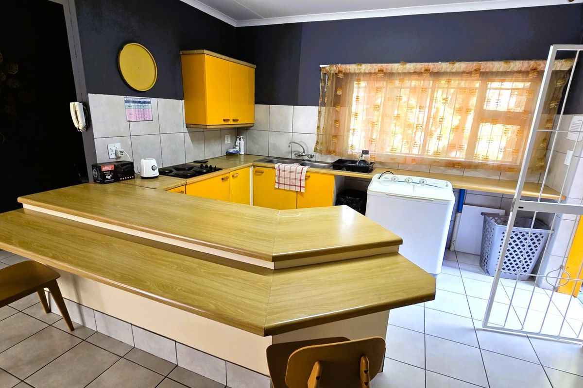 Functional kitchen featuring yellow cabinetry, a breakfast bar, gas hob, and tiled flooring, offering a practical layout with potential for modern updates.