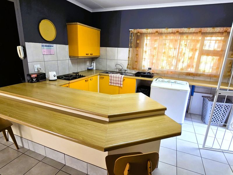 Functional kitchen featuring yellow cabinetry, a breakfast bar, gas hob, and tiled flooring, offering a practical layout with potential for modern updates.