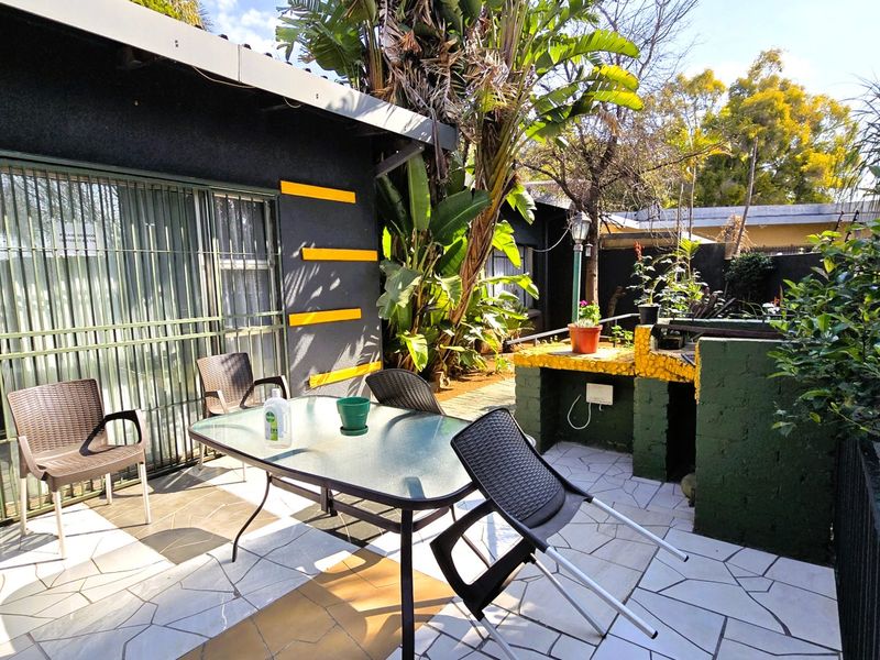 Outdoor patio area featuring a built-in braai, tiled flooring, and direct access to the interior via a sliding security door.