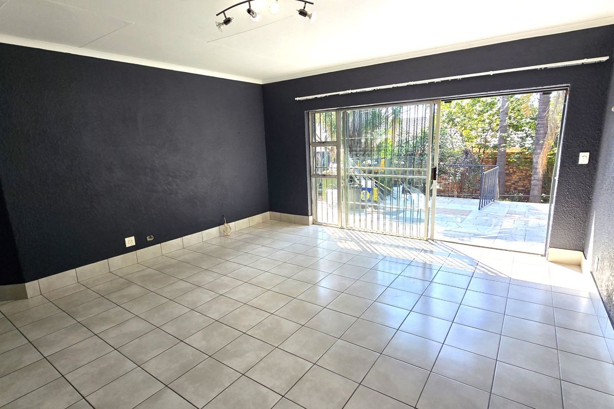 Spacious living area featuring neutral tiled flooring, dark accent walls, and a large sliding glass door providing direct access to the outdoor patio area.