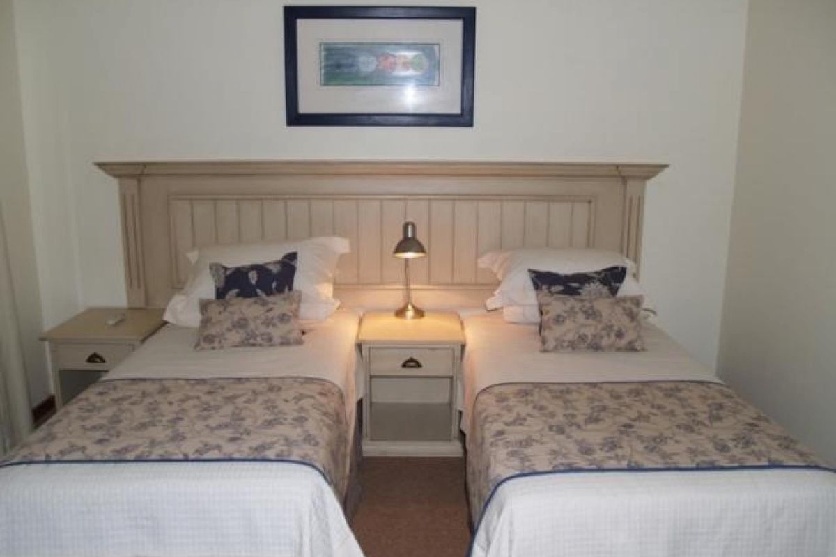 A bedroom featuring a neutral color palette with a built-in headboard and matching bedside tables.