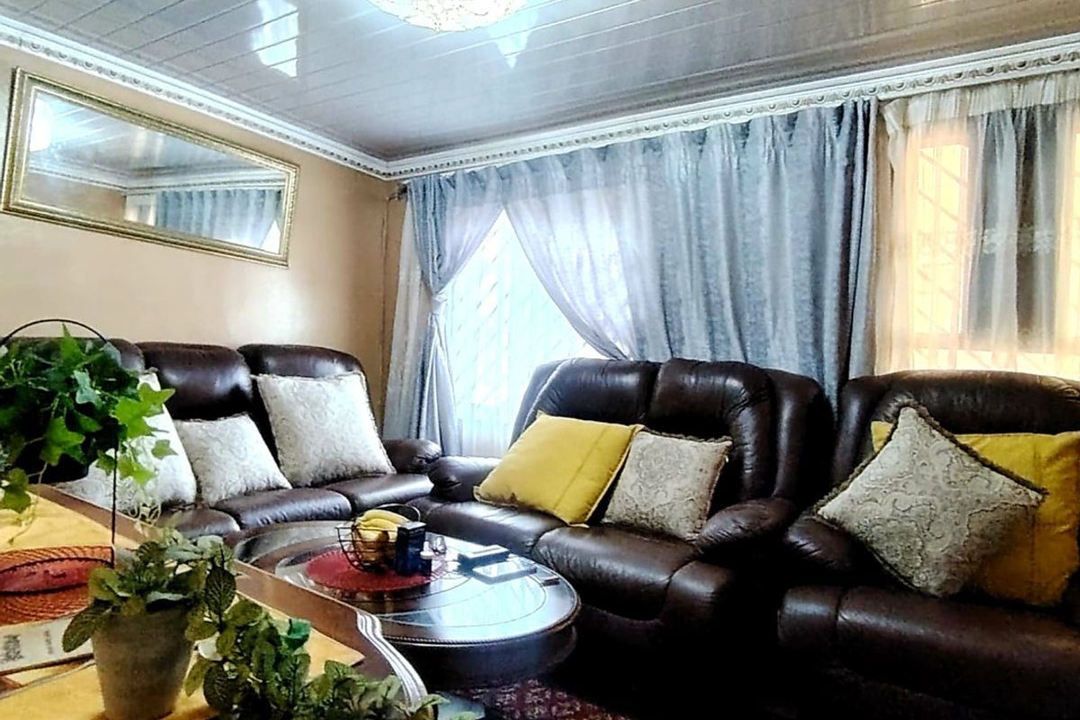 A living room featuring a glossy paneled ceiling, decorative crown molding, and an ornate chandelier, providing a traditional aesthetic.