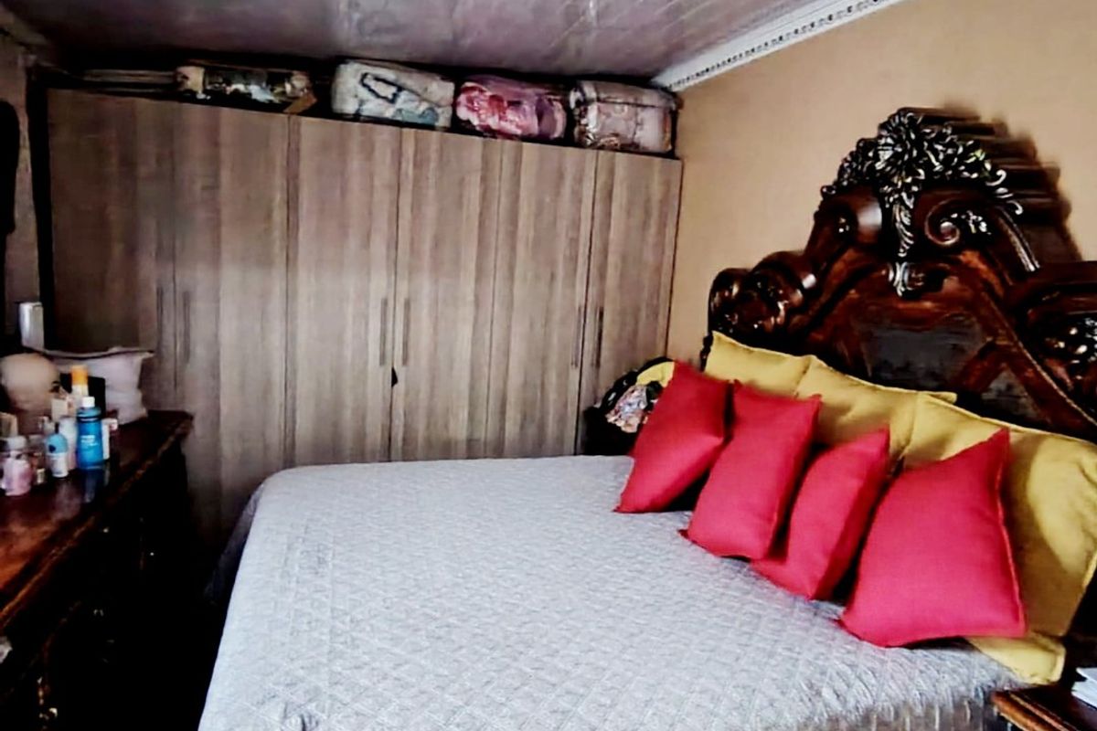 A bedroom featuring a built-in wardrobe and a white tongue and groove ceiling with decorative cornice detailing.