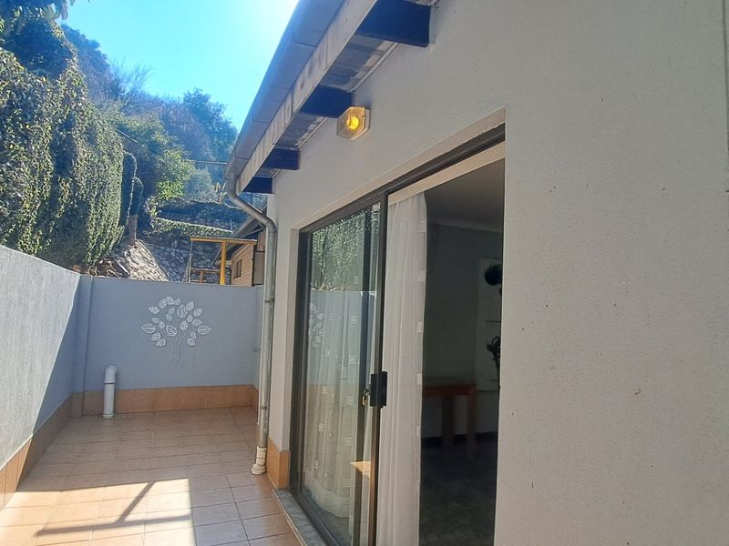 A private outdoor patio area featuring tiled flooring, a sliding glass door entrance, and a boundary wall, providing a seamless transition to the interior.