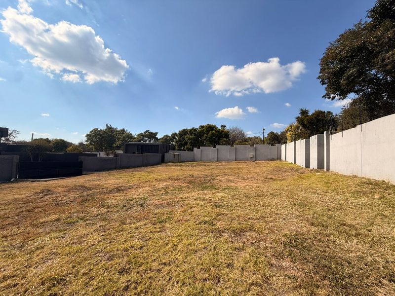 A vacant residential plot featuring a level grassed area enclosed by perimeter concrete walls.