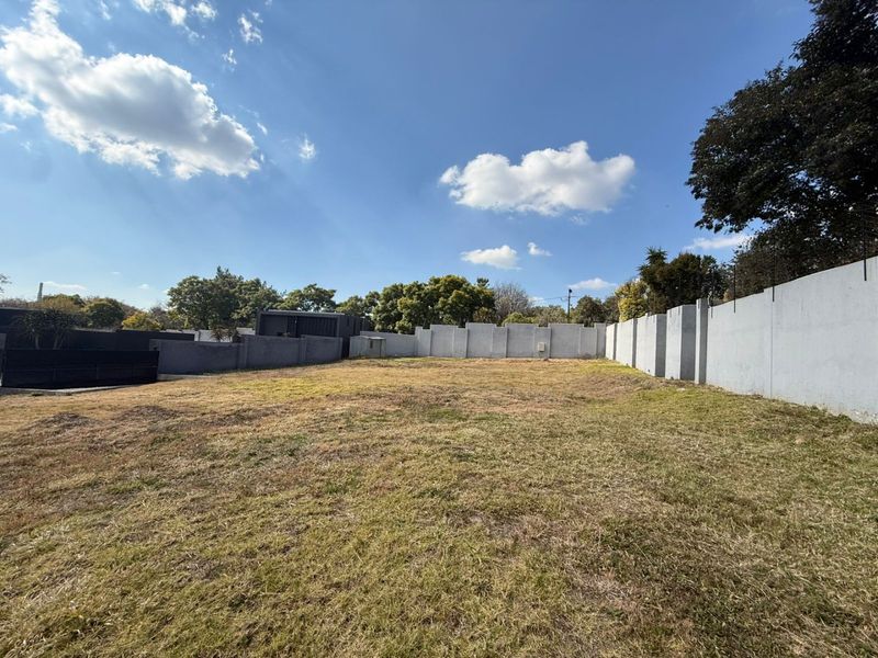 A spacious, level vacant residential plot enclosed by high perimeter boundary walls, offering a blank canvas for future development.