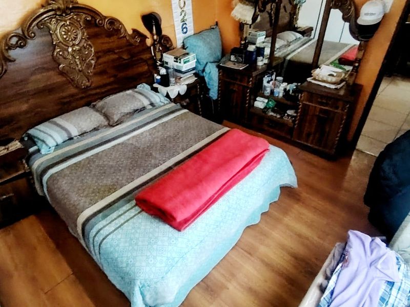 A bedroom featuring laminate flooring and orange wall paint.