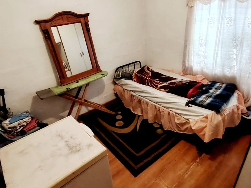 A bedroom featuring laminate flooring and a window with curtain rails, requiring cosmetic updates to improve the overall finish and appeal.