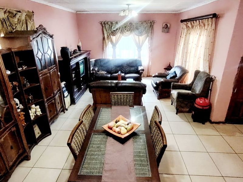 An open-plan living and dining area featuring tiled flooring and ceiling light fixtures, offering a spacious layout for family living.