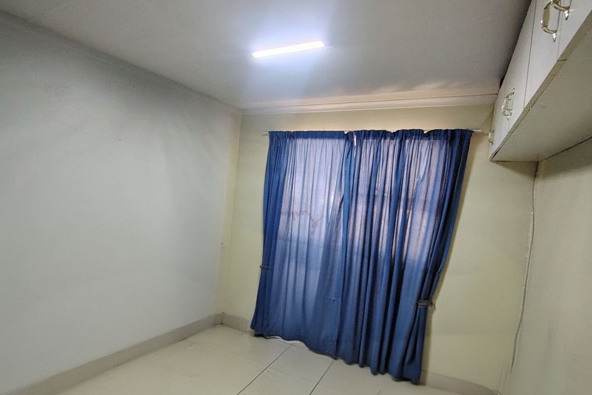 An empty bedroom featuring tiled flooring and built-in cupboards, providing a blank canvas for potential interior design updates.